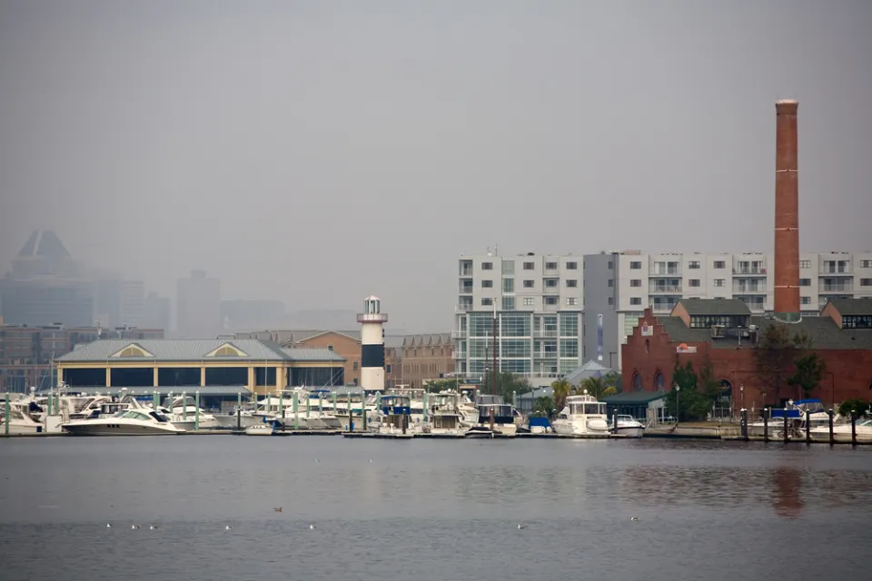The city of Baltimore's Inner Harbor blanketed in fog, as seen from the water.